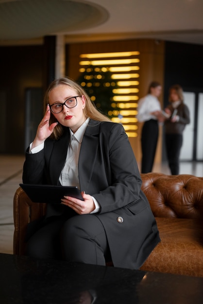 Mulher profissional em terno elegante no escritório com dispositivo tablet