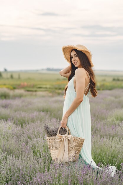 Mulher provençal relaxante no campo de lavanda. Senhora com um chapéu de palha. Menina com bolsa.