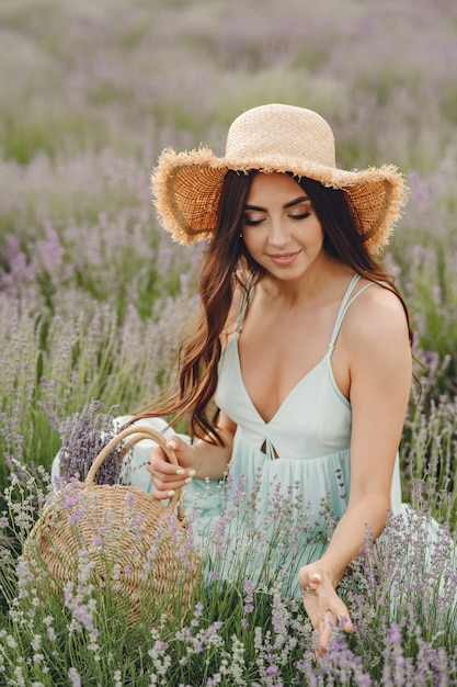 Mulher provençal relaxante no campo de lavanda. Senhora com um chapéu de palha. Menina com bolsa.