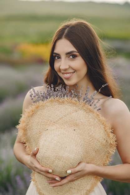 Mulher provençal relaxante no campo de lavanda. Senhora com um chapéu de palha.