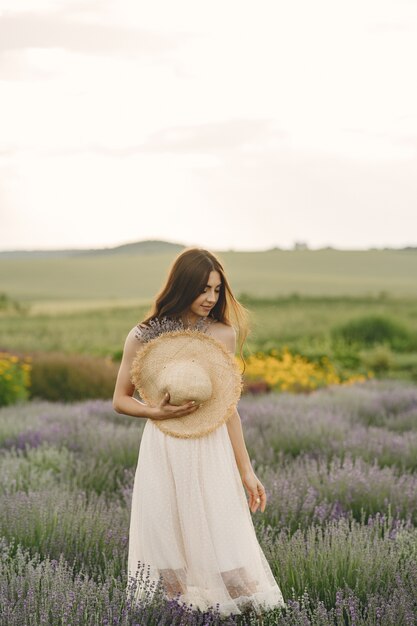 Mulher provençal relaxante no campo de lavanda. Senhora com um chapéu de palha.