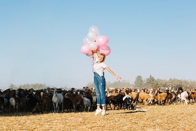 Mulher pulando com balões perto de cabras