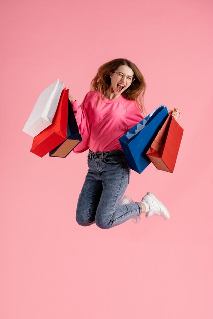 Mulher pulando com sacolas de compras