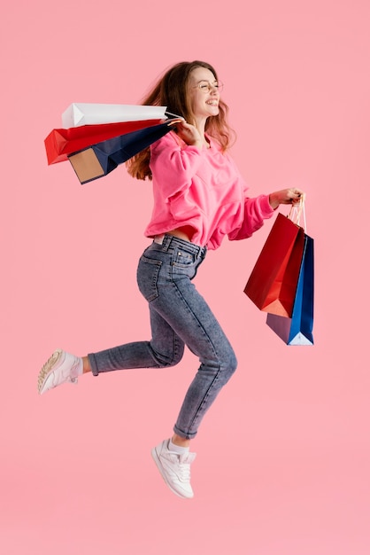 Mulher pulando com sacolas de compras