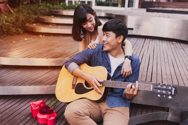 Mulher que abraça um homem enquanto ele toca guitarra