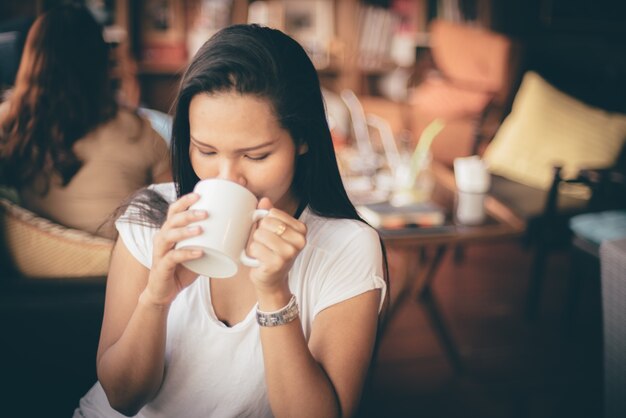 Mulher que bebe de uma chávena de café