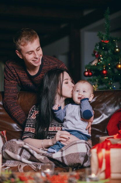 Mulher que beija seu bebê na cabeça, enquanto os sorrisos pai