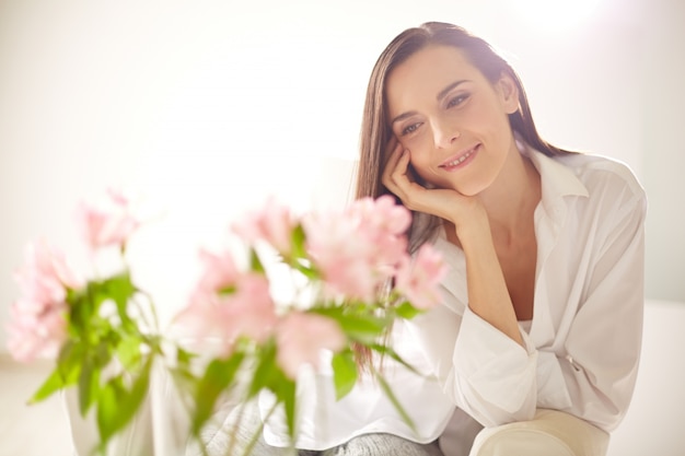 Mulher que contempla suas bonitas flores