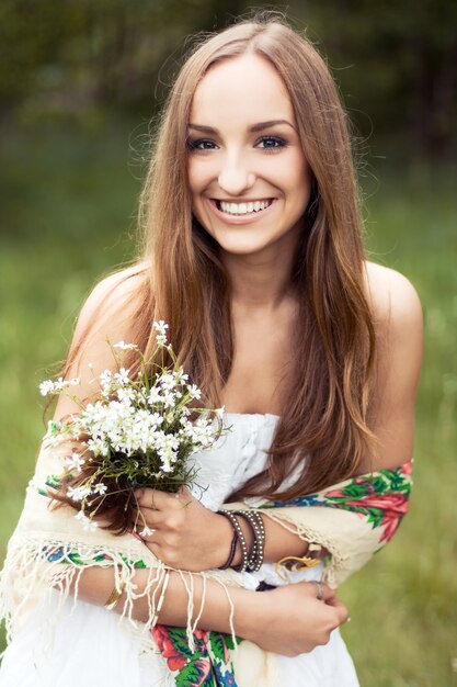 Mulher que desgasta um vestido branco e segurando flores