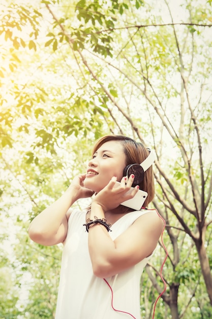 Mulher que escuta a música com fundo das árvores