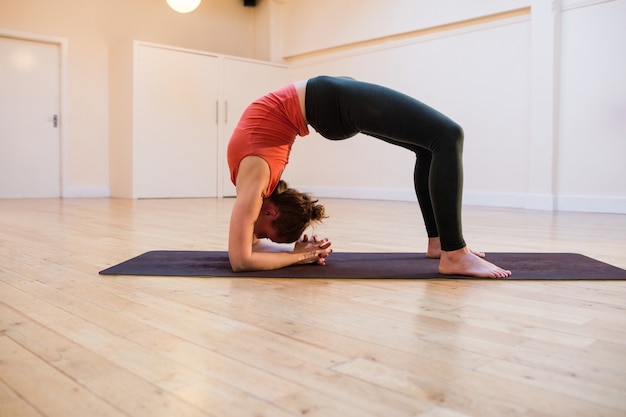 Mulher que executa chakrasana na esteira do exercício