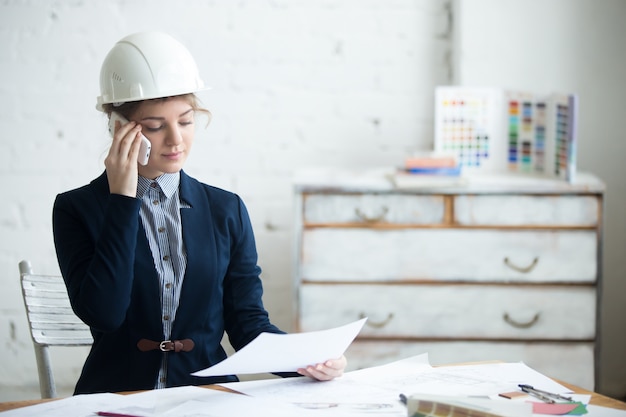 Mulher que fala em um telefone móvel com um capacete