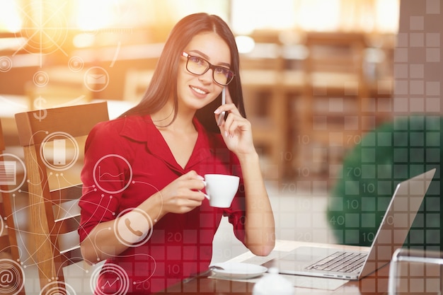 Mulher que fala no telefone com uma chávena de café