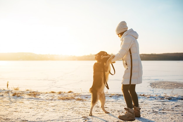 Mulher que joga com seu cão em um dia de inverno