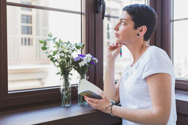 Mulher que pensa e que olha através da janela