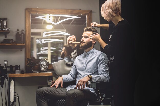 Mulher que penteia o cliente na barbearia