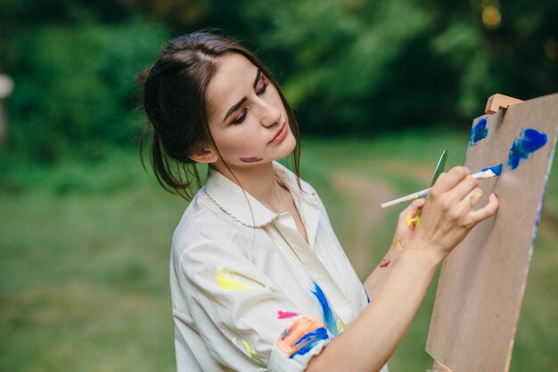 Mulher que pinta uma tela com cores azuis