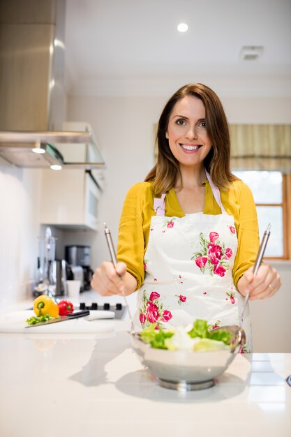 Mulher que prepara a salada na cozinha