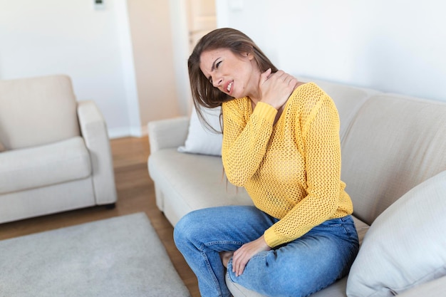 Foto grátis mulher que sofre de dor nas costas em casa dor nas costas mulher sente dor nas costas massageando músculos doloridos mulher triste sofre de dor nas costas