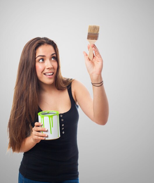 Mulher que sorri com uma lata de tinta verde