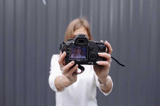 Mulher que toma uma foto de si mesma com uma câmera reflex