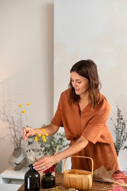 Foto grátis mulher que trabalha com plano médio de flores secas