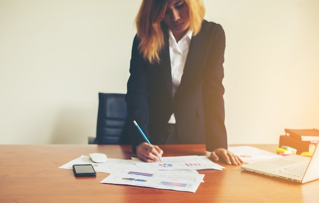 Mulher que trabalha em pé em gráficos