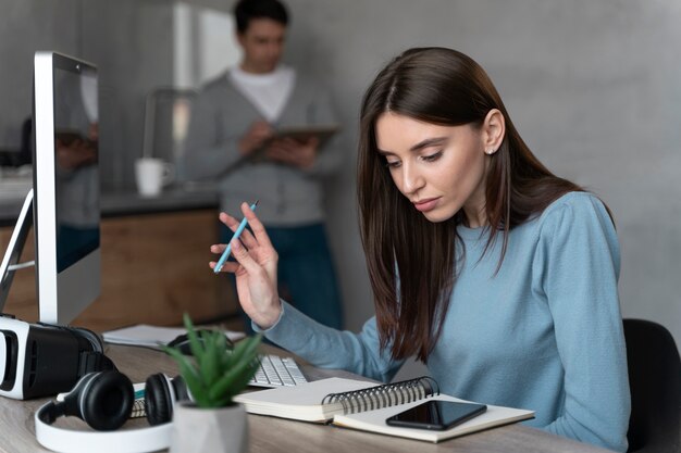 Mulher que trabalha na área de mídia com computador pessoal e smartphone