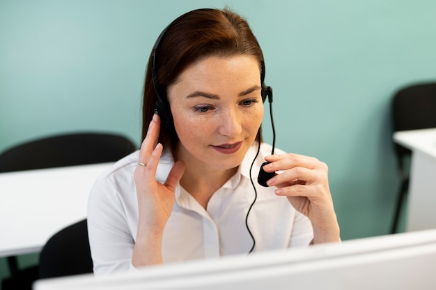 Mulher que trabalha no escritório de call center com fones de ouvido e computador