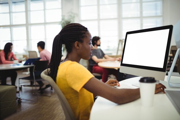 Mulher que usa o computador em sua mesa