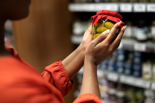 Mulher recebendo pote de picles no supermercado