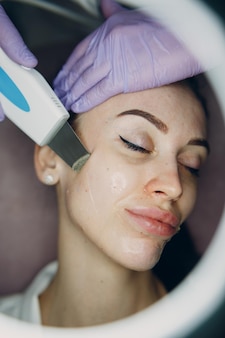 Mulher recebendo terapia de limpeza com um equipamento ultrassônico profissional no spa de beleza de cosmetologia.