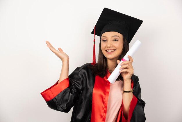 Mulher recém-graduada com diploma posando em fundo branco.