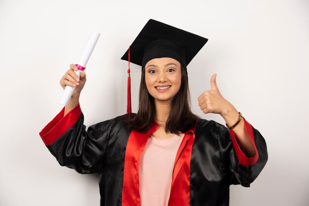 Mulher recém-graduada com diploma posando em fundo branco.