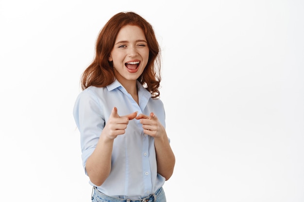 Mulher recrutando para o trabalho, apontando o dedo e piscando, convidando para se juntar a sua equipe, em pé de blusa branca.