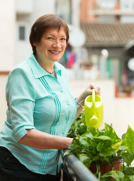 Mulher regando plantas na varanda