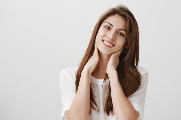 Mulher relaxada satisfeita tocando o pescoço e sorrindo, livrou-se da dor