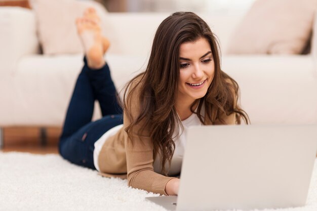 Mulher relaxada usando laptop em casa