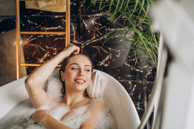 Mulher relaxando na banheira com bolhas