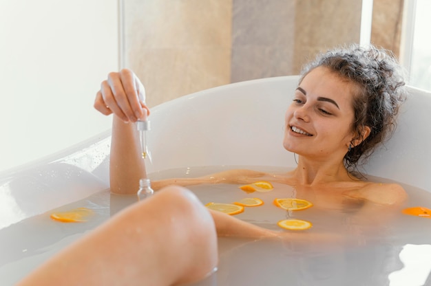 Mulher relaxando na banheira com rodelas de laranja