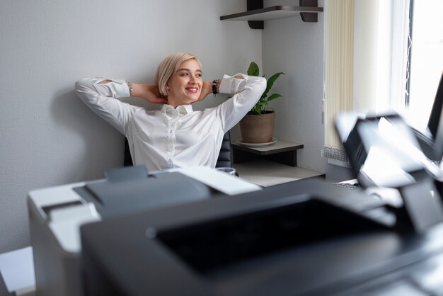 Mulher relaxando no escritório ao lado da impressora