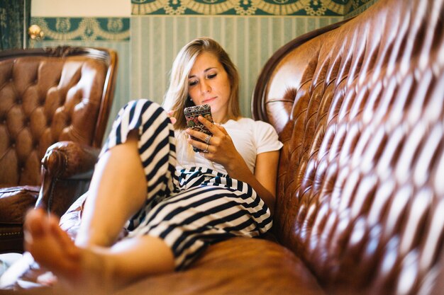 Mulher relaxante no sofá com smartphone
