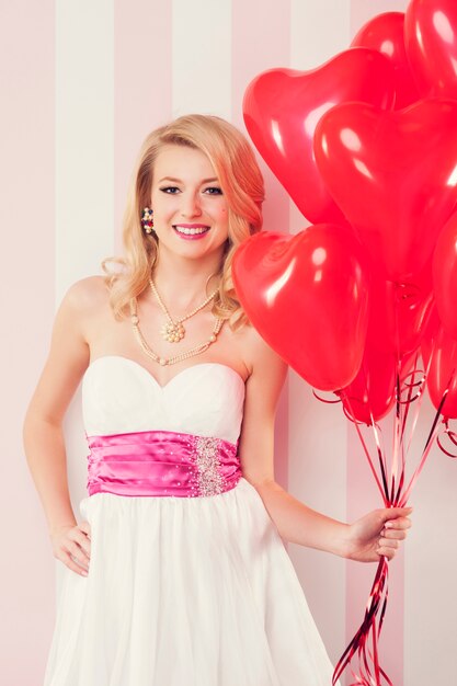 Mulher retro sorridente com balões vermelhos em forma de coração