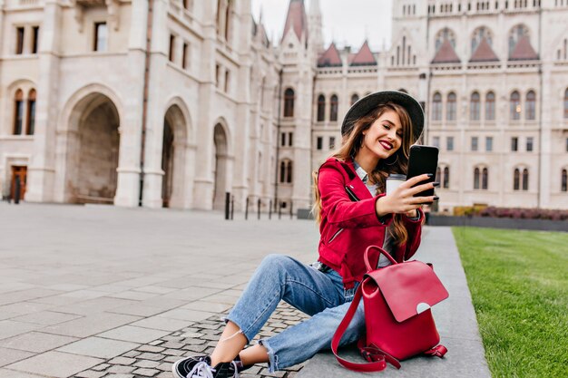 Mulher romântica em roupas casuais fazendo selfie com uma xícara de chá