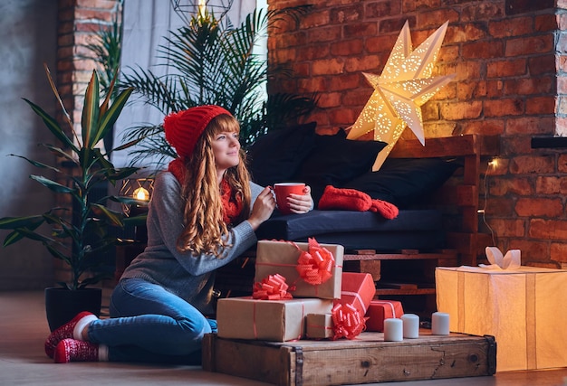 Mulher ruiva bebe um café quente em uma sala de estar com interior loft.