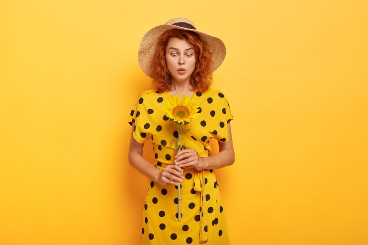Foto grátis mulher ruiva bonita e surpresa posando em um vestido polca amarelo e chapéu de palha