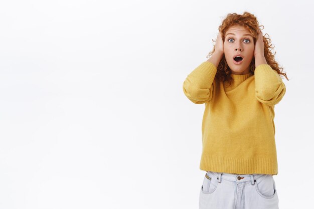 Mulher ruiva com cabelo encaracolado num suéter amarelo ofegante e atordoada