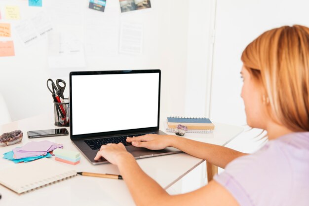 Mulher ruiva digitando no laptop na mesa com artigos de papelaria