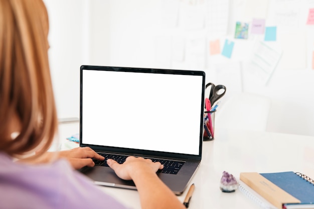 Mulher ruiva digitando no laptop na mesa perto da parede com notas