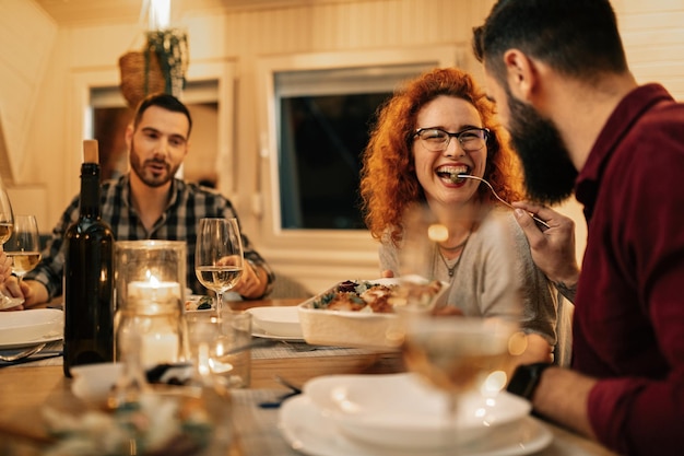 Mulher ruiva feliz se divertindo enquanto é alimentada pelo namorado durante uma refeição na sala de jantar
